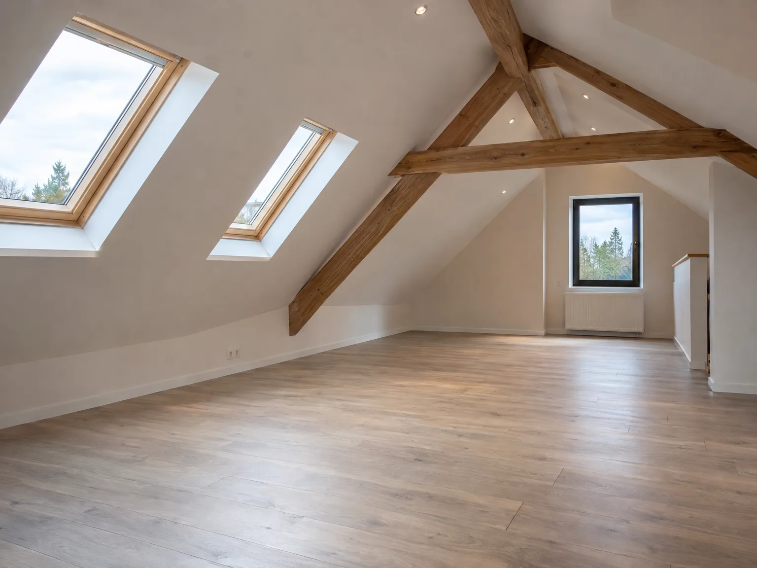 Espace de combles rénové avec poutres apparentes, fenêtres de toit et parquet